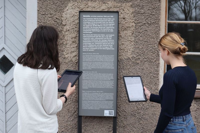 Teilnehmerinnen des Workshops erkunden den Außenbereich der sowjetischen Verwaltungsbaracke mit Ipads