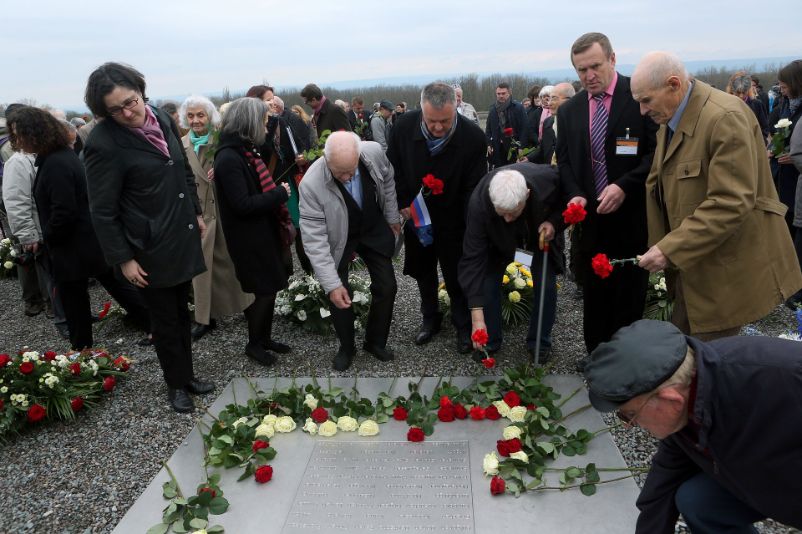 Teilnehmer:innen der Gedenkveranstaltung zum 75. Jahrestag legen Blumen auf dem Gedenkzeichen auf dem Appellplatz ab