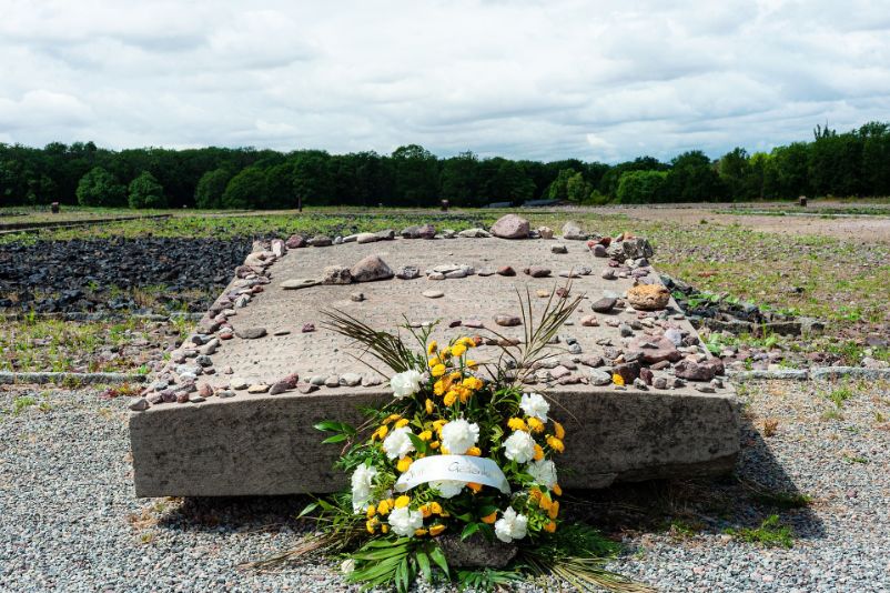 Grauer, mit kleinen Steinen belegter Gedenkstein mit der Gravierung: "Zum ehrenden Gedenken an die im KZ Buchenwald ermordeten Angehörigen der britischen und kanadischen Streitkräfte. Durch die Solidarität der deutschen Antifaschisten wurde das Leben von vier englischen Patrioten gerettet. Sie alle wurden in Block 17 gefangen gehalten." in Deutsch, English und Russisch.